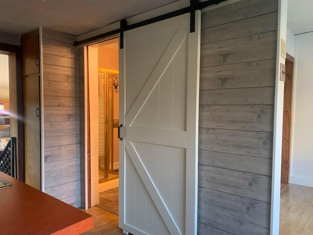 interior space featuring a barn door, wooden walls, and light wood-type flooring