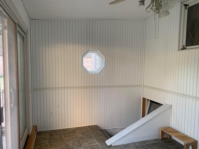 laundry room with ceiling fan and wood walls