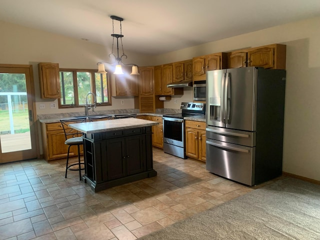 kitchen with appliances with stainless steel finishes, a breakfast bar, sink, a center island, and hanging light fixtures