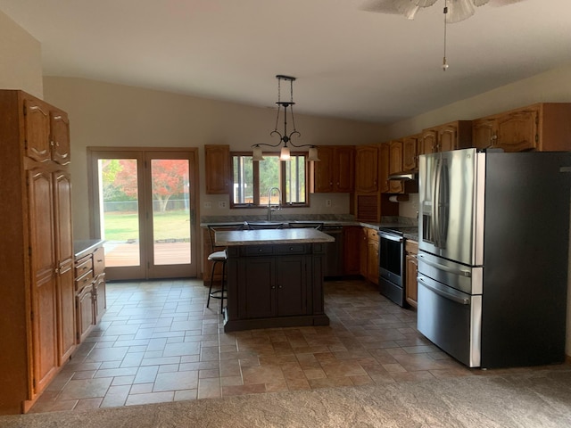 kitchen with hanging light fixtures, stainless steel appliances, vaulted ceiling, a kitchen island, and ceiling fan with notable chandelier