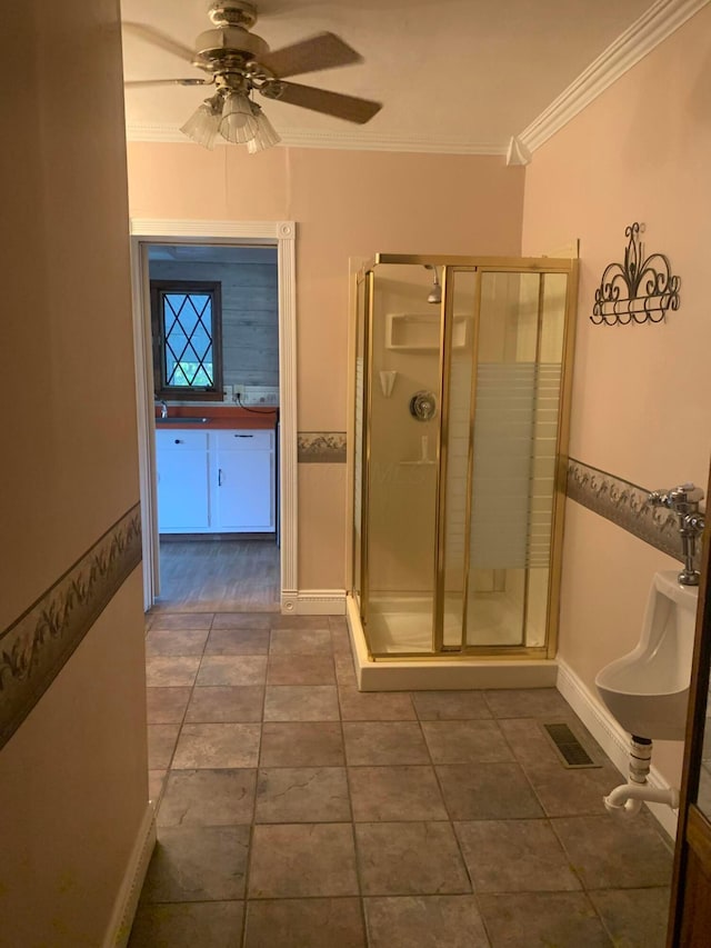 bathroom with ceiling fan, a shower with door, and ornamental molding