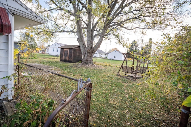 view of yard featuring a residential view, an outdoor structure, and fence