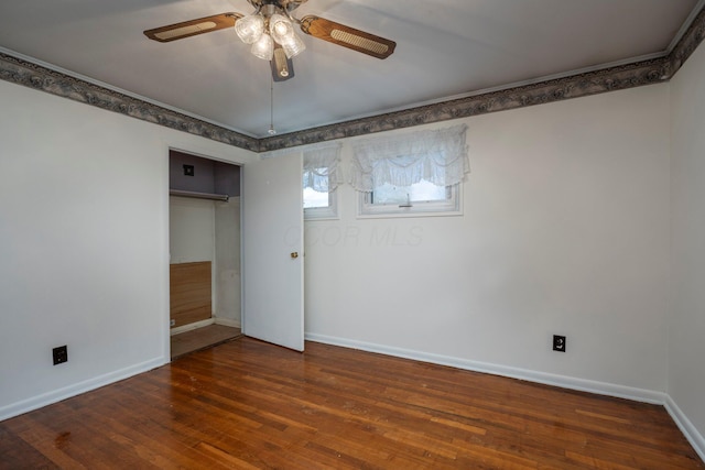 empty room with dark wood-style floors, a ceiling fan, and baseboards