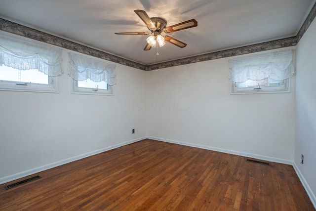 empty room featuring a ceiling fan, baseboards, visible vents, and wood finished floors