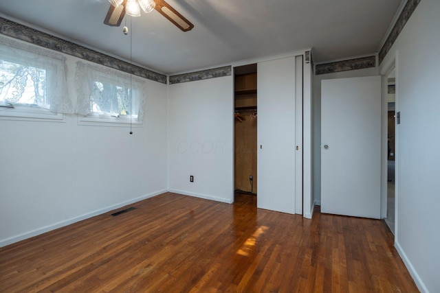 unfurnished bedroom featuring a closet, dark wood finished floors, visible vents, and baseboards