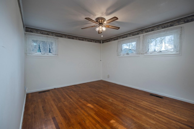 empty room with a ceiling fan, baseboards, visible vents, and dark wood-style flooring