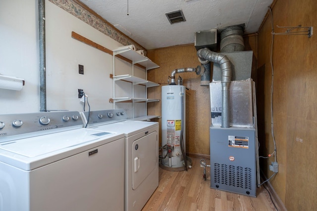 washroom featuring a textured ceiling, gas water heater, washing machine and dryer, light wood-style flooring, and laundry area