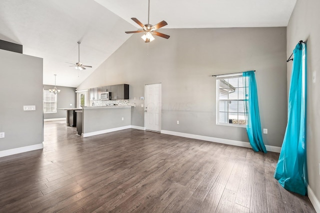 unfurnished living room with a healthy amount of sunlight, dark wood-type flooring, and high vaulted ceiling