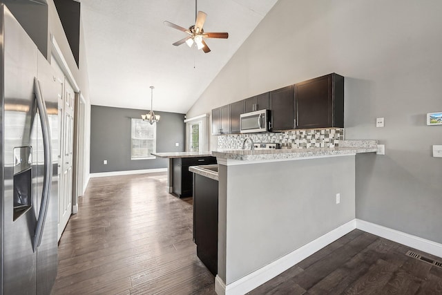 kitchen with kitchen peninsula, dark hardwood / wood-style flooring, high vaulted ceiling, and stainless steel appliances