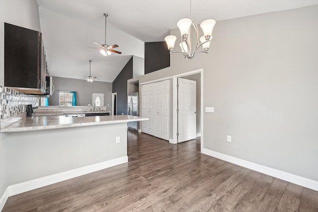 kitchen featuring kitchen peninsula, appliances with stainless steel finishes, dark brown cabinets, high vaulted ceiling, and dark hardwood / wood-style floors