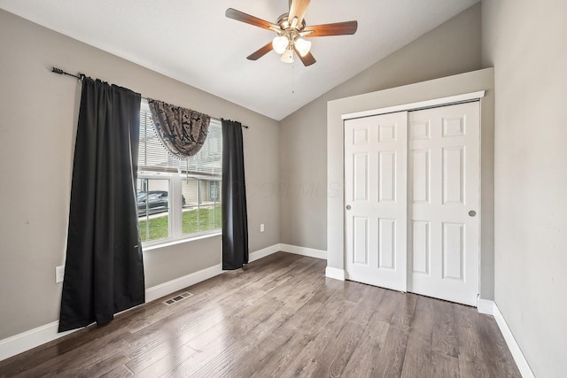 unfurnished bedroom featuring hardwood / wood-style flooring, ceiling fan, lofted ceiling, and a closet