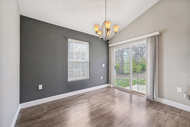 empty room featuring a chandelier, lofted ceiling, and hardwood / wood-style flooring