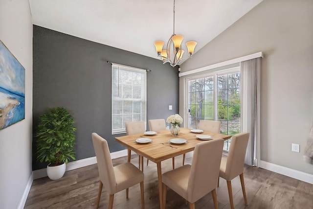 dining room featuring dark hardwood / wood-style flooring, an inviting chandelier, and vaulted ceiling