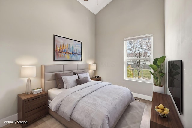 bedroom featuring light wood-type flooring and high vaulted ceiling