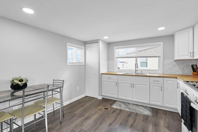 kitchen with backsplash, sink, white cabinetry, and dark wood-type flooring