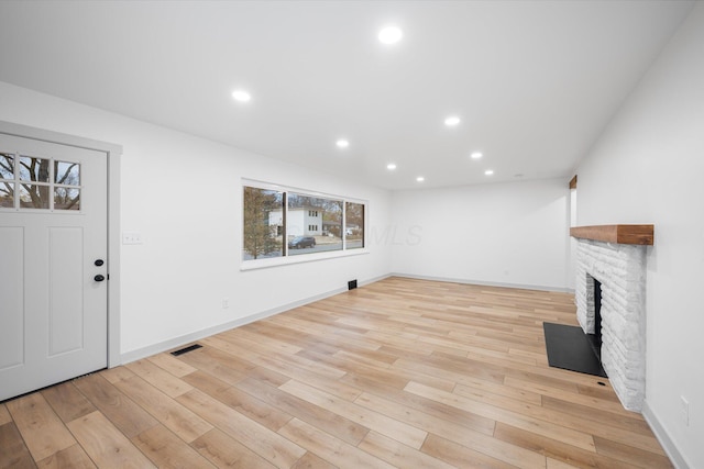 unfurnished living room with a brick fireplace and light hardwood / wood-style flooring