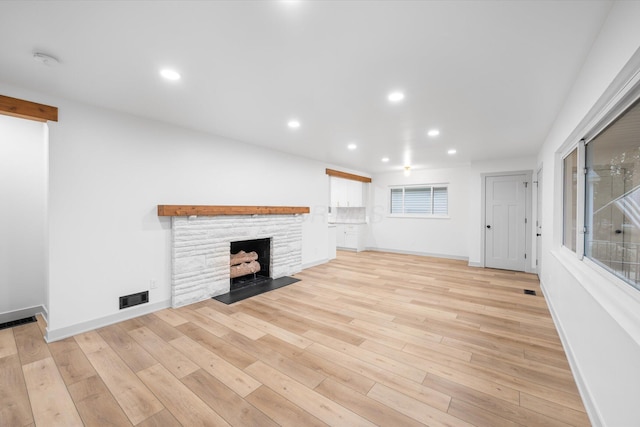 unfurnished living room featuring a fireplace and light hardwood / wood-style floors