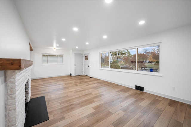 unfurnished living room with a stone fireplace and light hardwood / wood-style flooring