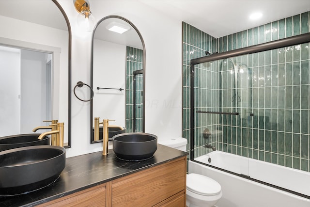 full bathroom featuring combined bath / shower with glass door, vanity, and toilet