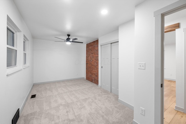 unfurnished bedroom featuring a closet, light colored carpet, and ceiling fan