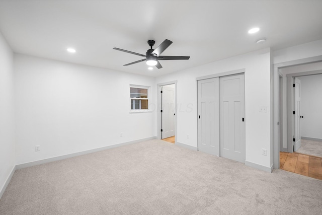 unfurnished bedroom featuring ceiling fan, a closet, and light carpet