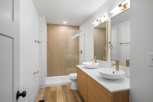 bathroom featuring tiled shower, toilet, vanity, and hardwood / wood-style flooring