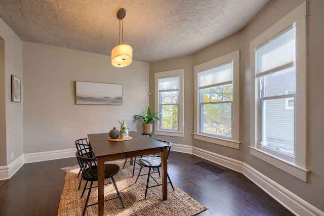 dining room featuring a textured ceiling and dark wood-type flooring