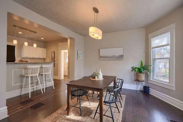 dining area with dark hardwood / wood-style flooring and a textured ceiling