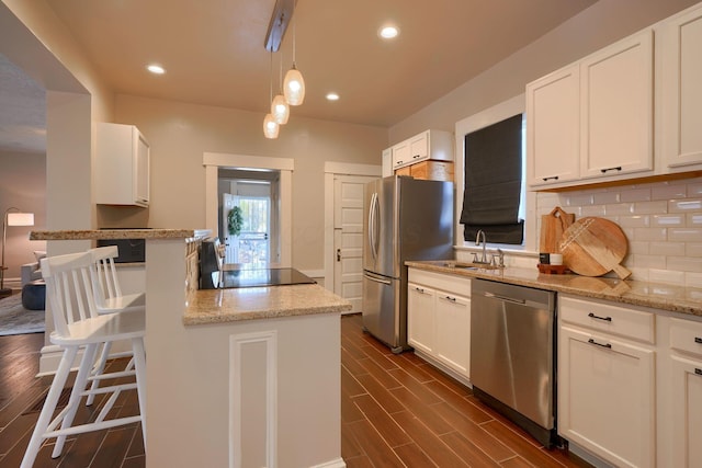 kitchen featuring sink, stainless steel appliances, dark hardwood / wood-style floors, decorative light fixtures, and white cabinets