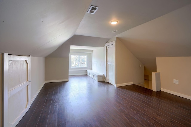 additional living space featuring dark wood-type flooring and lofted ceiling