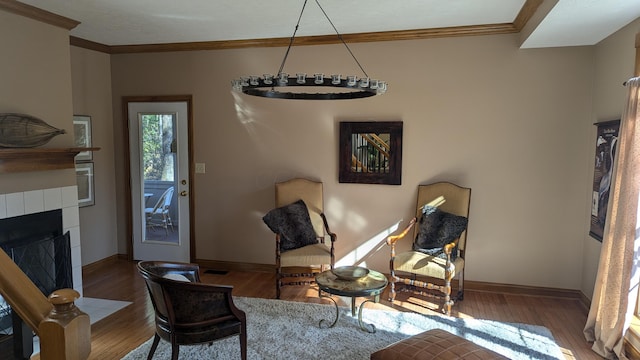 sitting room with wood-type flooring, ornamental molding, and a tiled fireplace