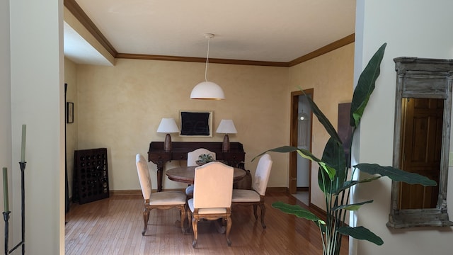 dining space with hardwood / wood-style flooring and crown molding