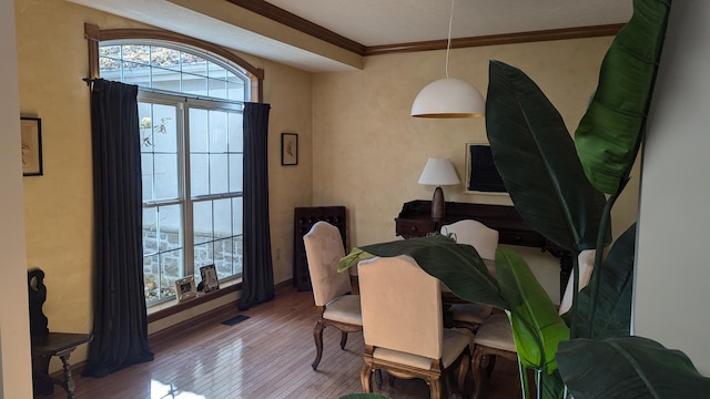 dining space with wood-type flooring and crown molding