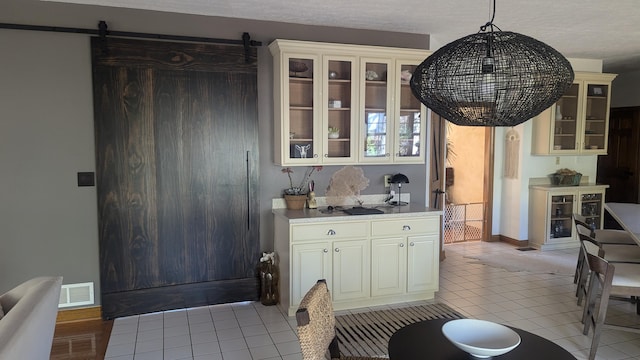 kitchen featuring decorative light fixtures, a barn door, light tile patterned flooring, and a textured ceiling