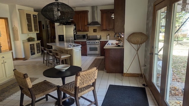 kitchen with pendant lighting, wall chimney range hood, sink, appliances with stainless steel finishes, and a kitchen island