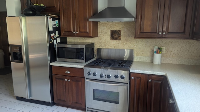 kitchen with backsplash, light tile patterned flooring, wall chimney range hood, and stainless steel appliances