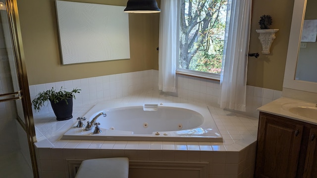 bathroom with tiled tub and vanity