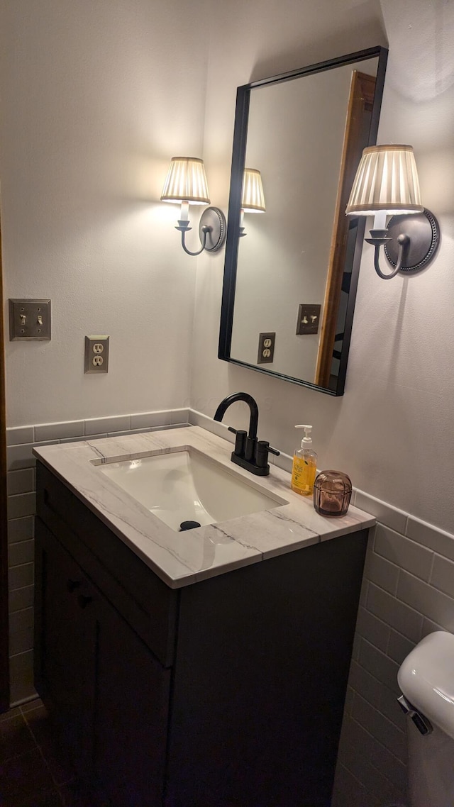 bathroom featuring vanity, tile walls, and toilet