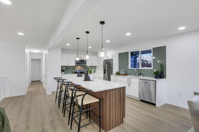 kitchen featuring white cabinets, light wood-type flooring, stainless steel appliances, and a kitchen island