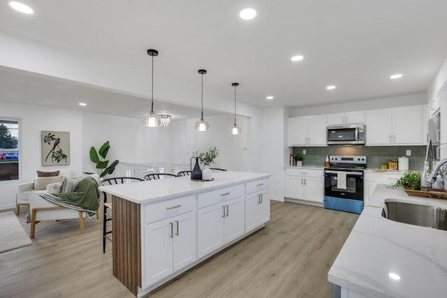 kitchen with sink, white cabinetry, stainless steel appliances, and light hardwood / wood-style flooring