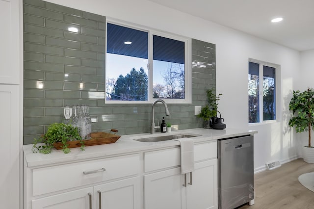 bar with light stone countertops, sink, dishwasher, light hardwood / wood-style flooring, and white cabinets