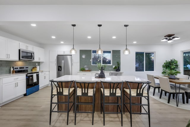 kitchen featuring white cabinets, a center island, hanging light fixtures, and appliances with stainless steel finishes