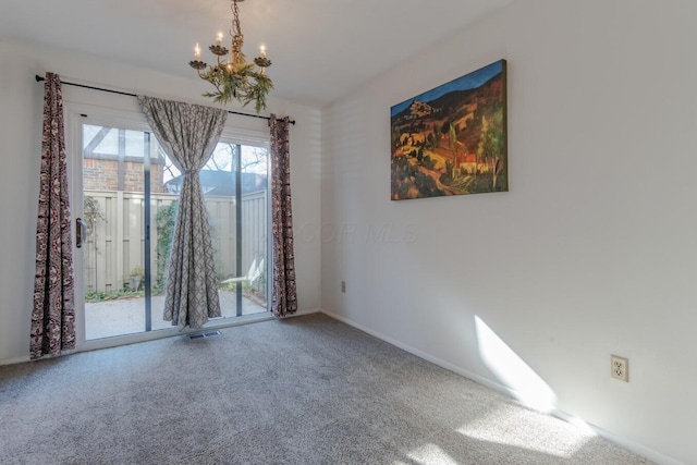 carpeted spare room featuring a chandelier