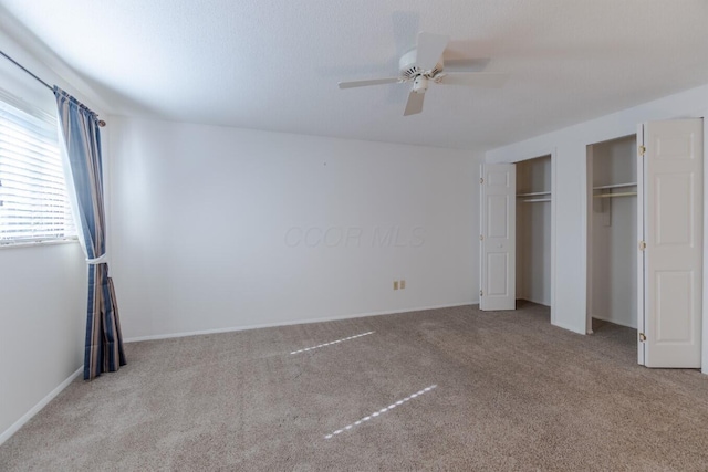 unfurnished bedroom featuring ceiling fan, light colored carpet, and multiple closets