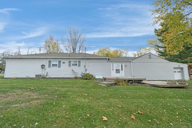 rear view of house with cooling unit, a garage, and a yard