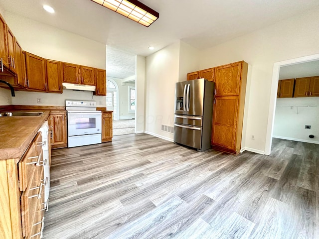 kitchen featuring stainless steel fridge, sink, light hardwood / wood-style floors, and white electric stove