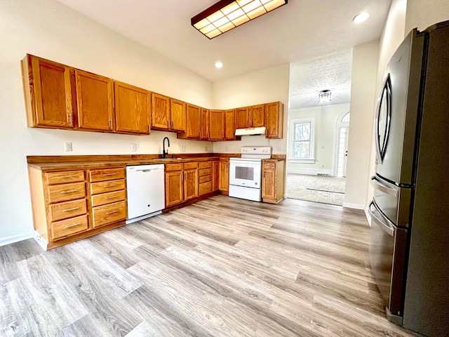 kitchen with white appliances, sink, and light hardwood / wood-style flooring