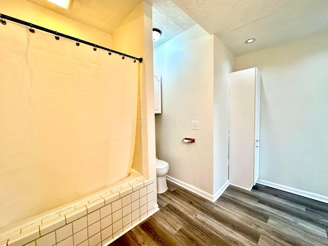 bathroom with hardwood / wood-style floors, shower / bathtub combination, toilet, and a textured ceiling