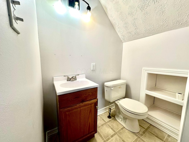 bathroom with vanity, toilet, and lofted ceiling