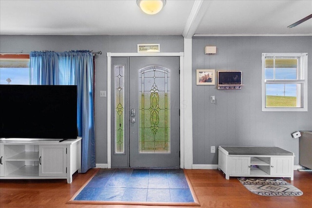 entryway featuring hardwood / wood-style floors, beam ceiling, ornamental molding, and wooden walls